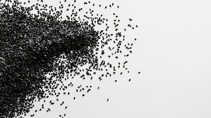 Fototapeta premium Artfully scattered black sesame seeds on a white background emphasize their vibrant color and texture in a minimalist display, showcasing their natural allure and culinary possibilities.