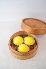 Warm Steamed Custard Buns With Golden Lava Filling And Smooth Yellow Surface Presented In Traditional Bamboo Steamer.