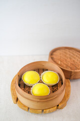 Bright Yellow Steamed Buns Served Hot In Bamboo Steamer To Show Soft And Creamy Texture Showing.