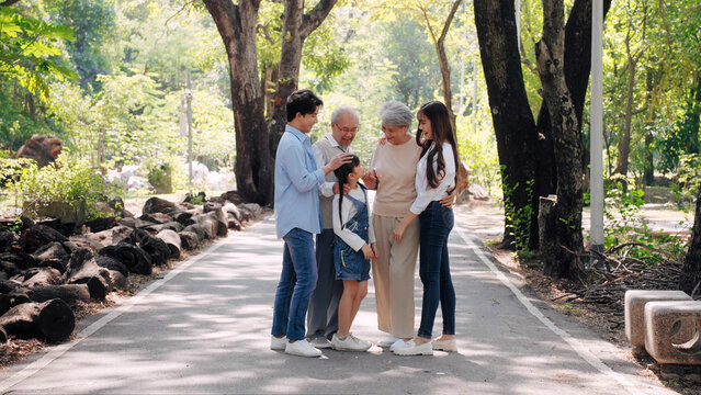 Happy Multi-generation Asian families smiling relax and socialize in the park, Big family standing in the public outdoor garden concept
