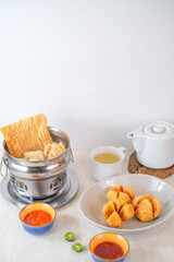 Warm Indonesian Cuanki Soup With Crispy Fried Dumplings, Fish Balls, Lime, Chili Sauces, And Hot Tea Presented For A Cozy And Flavorful Experience.