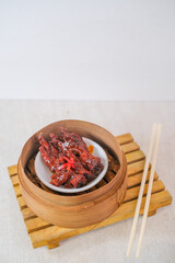 Flavorful Chicken Feet With Spicy Savory Sauce Served In Bamboo Steamer Perfect For Dim Sum Lovers And Authentic Culinary Experience.