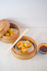 Juicy Steamed Siomay Dumplings Presented In Bamboo Baskets With A Side Of Flavorful Chili Sauce For An Authentic, Savory, And Heartwarming Dim Sum.