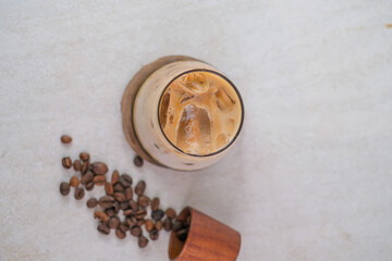 Iced Coffee In A Glass Mixed With Creamy Milk And Palm Sugar On Wooden Coaster, Decorated With Scattered Coffee Beans For A Rich And Refreshing Taste.