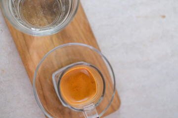 Shot Of Freshly Brewed Espresso With Rich Crema And Clear Water On Wooden Tray For A Balanced And Refreshing Coffee Experience.