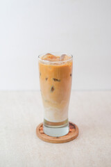 Iced Cappuccino In Tall Clear Glass With Milk And Espresso Layers Served On Wooden Coaster Against Light Background Perfect For A Refreshing Treat.
