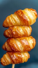 Golden Brown Croissant Stacked on Skewers Against a Soft Background