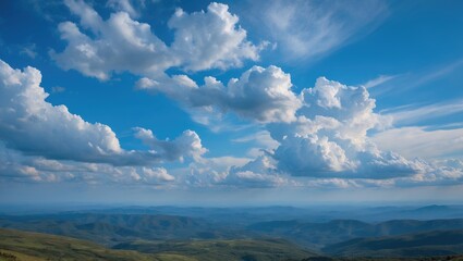 Obraz premium Mountain landscape with expansive blue sky and fluffy clouds over rolling hills and valleys during daytime.