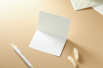 Blank Greeting Card and Pen on a Soft, Neutral-Toned Surface With Decorative Dried Flowers Arranged...