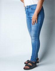 Woman Wearing Blue Skinny Jeans and Sandals, Posing Against a Neutral Background