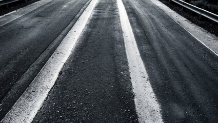 Textured asphalt road in monochrome with visible lane markings and rugged surface, illustrating urban decay and minimalism.