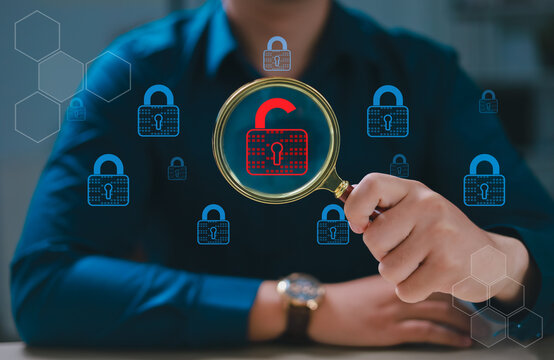 Hand holding magnifying glass, security engineer identifying data security vulnerabilities in internet network, unlocked padlock icon and many more locked padlock icons.