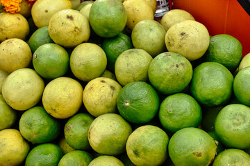Limes and lemons are piled high at a bustling market, showcasing their fresh, vibrant colors against a bright backdrop
