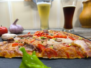 delicious slice of pizza lies on a sliced board, with glasses of beer in the background