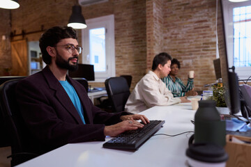 Focused employee typing on keyboard in busy office