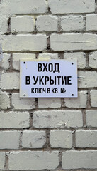 entrance to the shelter, sign on the brick wall in Russian