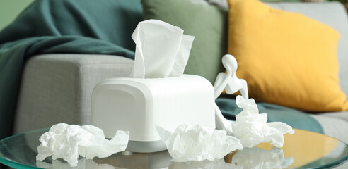 White paper tissue box and crumpled tissues on glass coffee table in living room