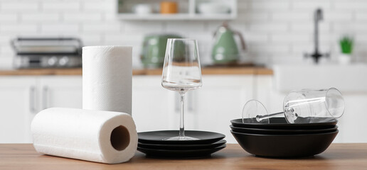 Rolls of paper towels with plates and glasses on kitchen table