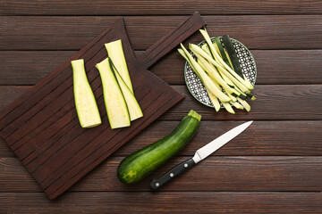 Board and plate with slices of fresh green zucchini on wooden background