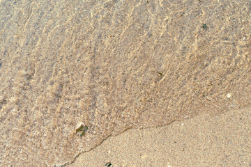 Soft waves gently lap against a sandy shore, creating a serene tropical atmosphere.