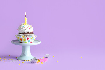 Stand of delicious birthday cupcake with burning candle on purple background