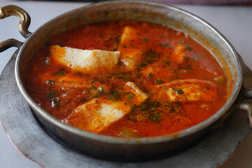 Spicy curry with paneer served in traditional metal dish
