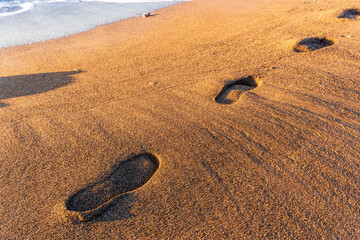 footstep track on sea shore sand with vawes and surf on background