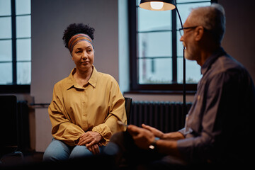 Mature woman participating in group therapy meeting at community center.