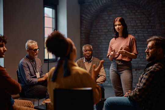 Young woman talking while attending mental health support group session at community center.