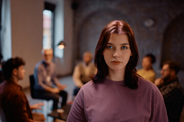 Young woman participating in mental health therapy session at community center and looking at...