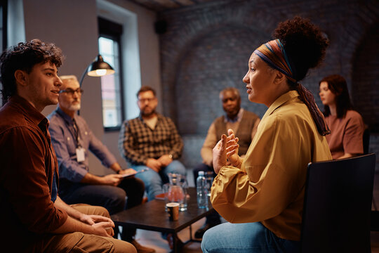 Group of diverse people talking while having group meeting with their therapist at mental health center