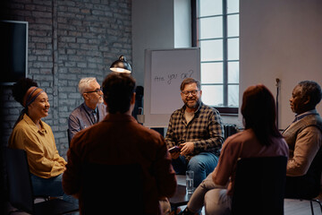 Happy mature man talking during group therapy at mental health center.