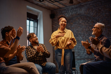 Happy woman receiving applause from participants of group therapy after talking about her mental...