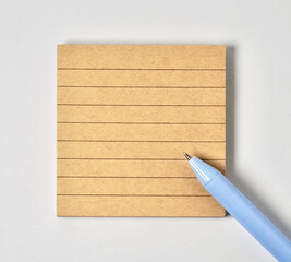 Brown square lined empty note paper isolated on white background from top angle view with blue...