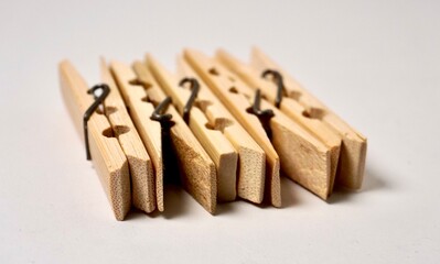 Five wooden clothes peg object isolated on horizontal plain background.
