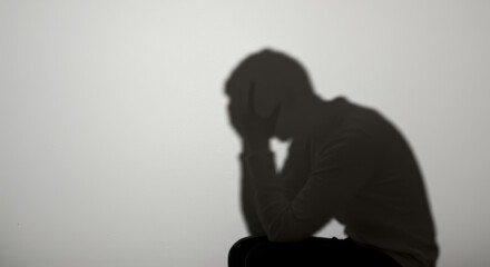 Shadow of a person with head in hands symbolizing stress and financial worry