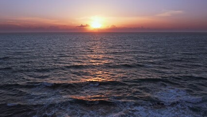 Aerial view over beautiful  ocean during  sunset. Top view to the ocean in summer day while sunset - closeup. Drone view of a Scenic slow motion ocean waves. Beautiful sunrise over ocean
