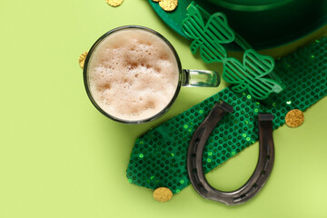 Mug of dark beer with leprechaun hat, plastic eyeglasses and horseshoe on green background. St....