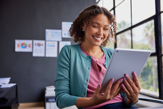 Smiling multiethnic casual woman using tablet at coworking space