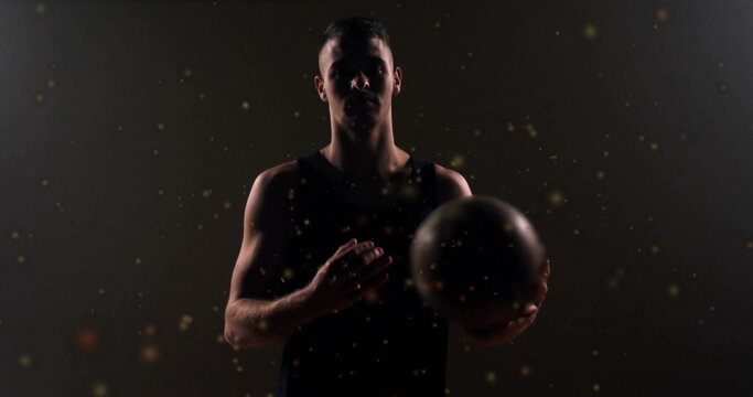 Image of moving spots over caucasian male basketball player holding basketball