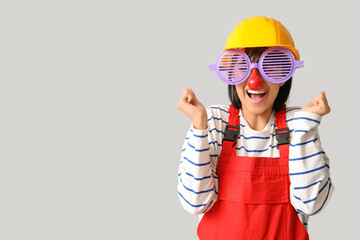 Young female builder with hardhat and funny glasses on white background. Fool's day