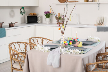 Festive table serving with painted eggs, flowers and burning candles for Easter celebration