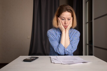 Utility bill shock, woman stressed by high gas and electricity costs, holding a receipt and looking at it with confusion