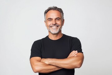 Fototapeta premium Smiling middle aged man with his arms crossed, wearing a black t shirt on white background.