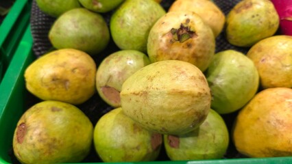 Fresh guava fruit with vibrant green skin and juicy pink flesh, sliced and arranged on a wooden surface. The tropical fruit is rich in vitamin C antioxidants, perfect for healthy eating natural food