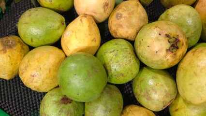 Fresh guava fruit with vibrant green skin and juicy pink flesh, sliced and arranged on a wooden surface. The tropical fruit is rich in vitamin C antioxidants, perfect for healthy eating natural food