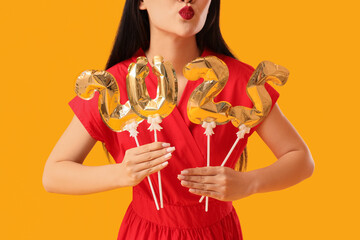 Beautiful Asian woman with balloons in shape of figure 2025 on yellow background