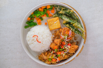 Rice With Spiced Garlic Fried Chicken, Crispy Vegetables, Fried Tofu, And Fresh Chili Garnish Neatly Served In A Bowl For A Colorful And Tasty Meal.