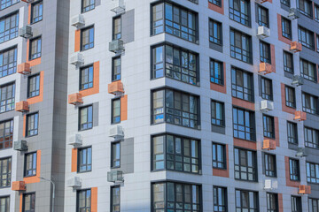 Fototapeta premium The concept of modern architecture, a residential complex, an apartment building for living. Close-up of the corner of the house in the camera multi-storey, apartment building in gray and white tones