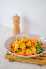 Fried Tofu With Salt And Chili, Topped With Scallions And Parsley, Presented In A White Bowl On A Wooden Board For A Perfect Snack.